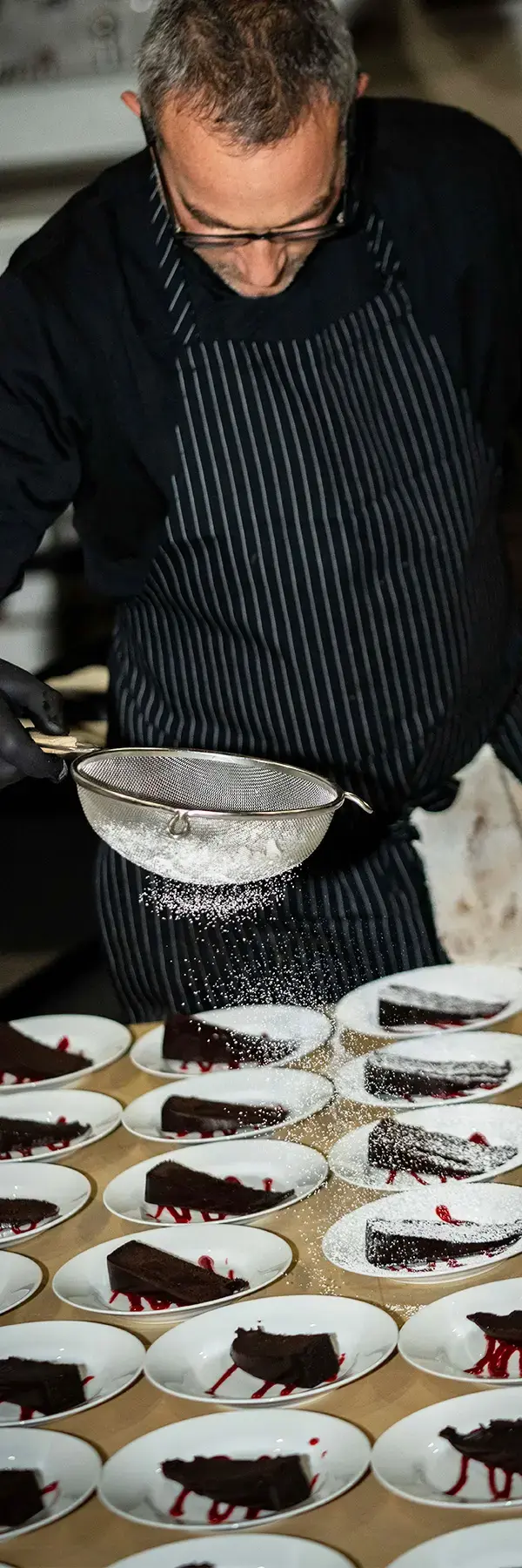 A picture of a chef preparing cake slices for a large crowd