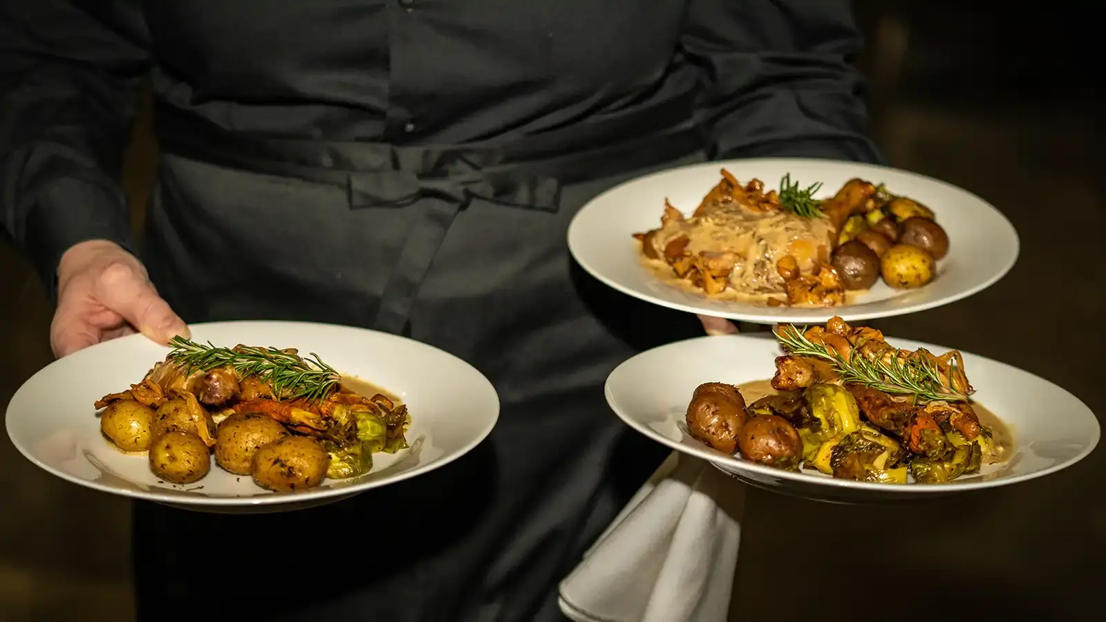 A server carrying three plates of food