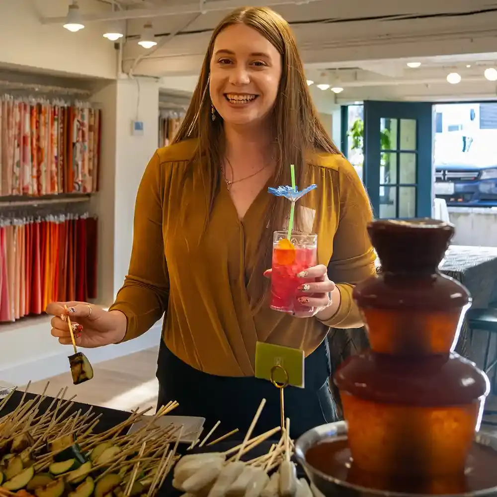 A smiling guest with a tropical drink in her hand about to enjoy an appetizer